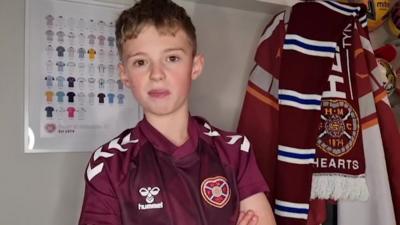 boy in a hearts shirt with scarves behind him