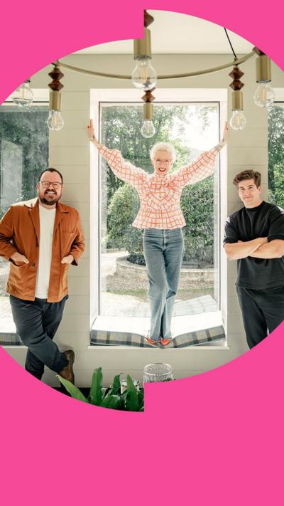 Three presenters stand in front of glass windows