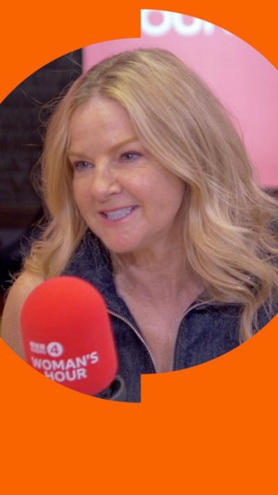A woman with long, blonde hair talks into a microphone