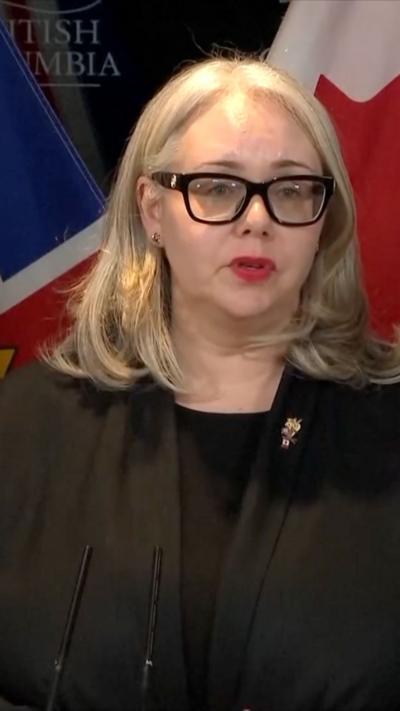 Nina Krieger standing in front of Canadian flag at a news conference