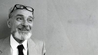 A black and white portrait of Primo Levi smiling.