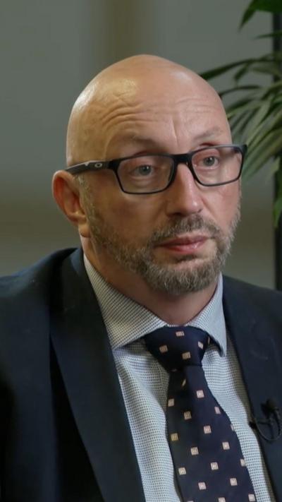 A bald man wearing glasses and a suit