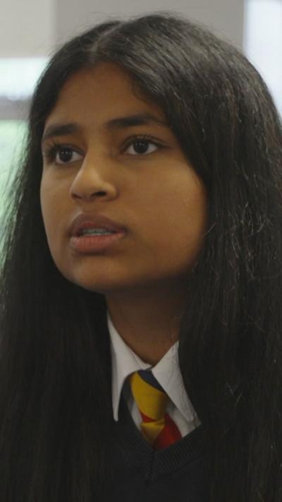 A woman with dark hair stares off camera.
