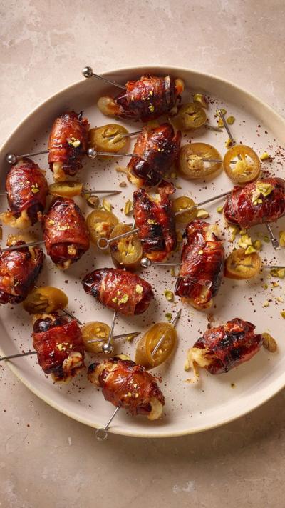 A bowl containinf dates wrapped in proscuitto on skewers with jalapeno peppers