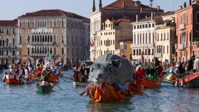 A boat carries a "Pantegana", the big rat, as revellers row during the masquerade parade on the Grand Canal during the Venice Carnival, in Venice, Italy.