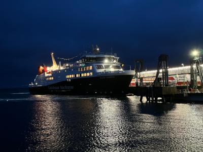 MV Glen Sannox at Arran. It is dark outside and the ship's lights are lit up.