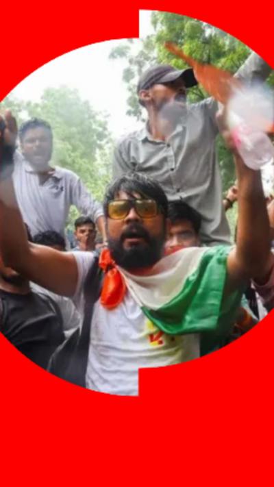 Man with dark hair wearing a white t-shirt with the India flag draped over his shoulders.