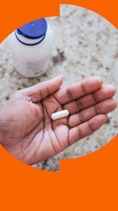A supplement in a hand with a bottle in the background