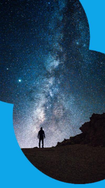 Silhouette of a person on a hilltop observing the Milky Way in the sky.