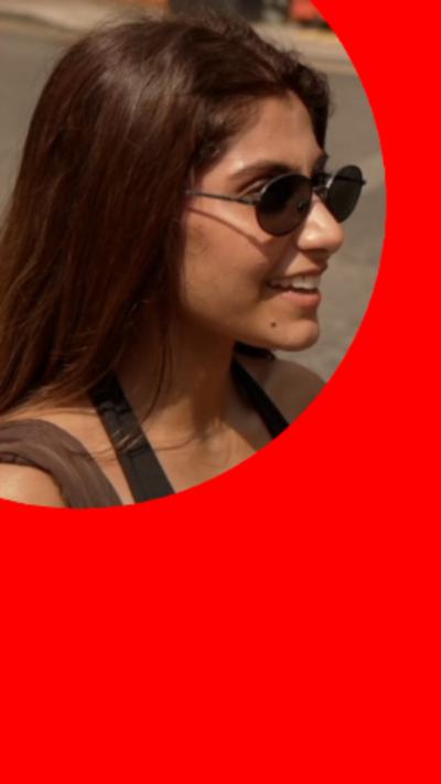 Young woman with long brown hair, wearing sunglasses.
