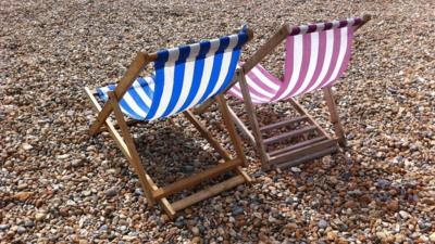 Two deck chairs on a pebble beach