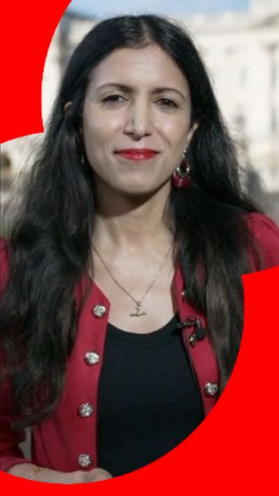 BBC Journalist Noon Nanji has long dark hair and is wearing a red jacket over a black top.