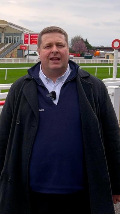 A man looking into the lens with a blue jumper and coat on