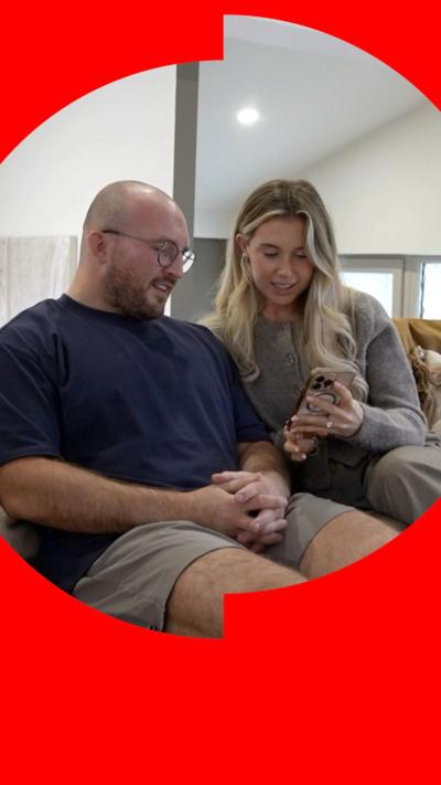 Man and women sitting on a couch looking at a phone