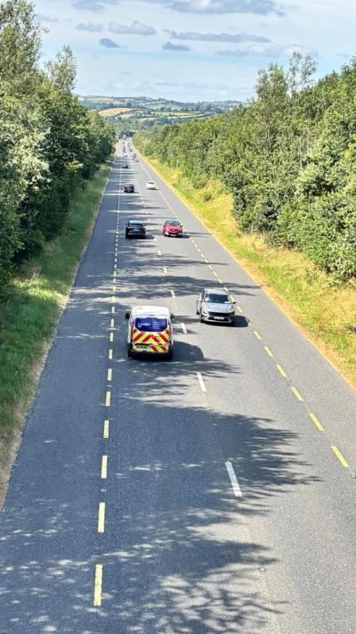 A still of the N2 road in Carrickmacross in County Monaghan. It is a single-file road with traffic flowing in each direction.