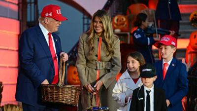 Donald Trump and Melania Trump greet kids dressed as Trump and Melania Trump with a Secret Service officer.