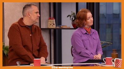 Dr Xand and Iona Bain in the Morning Live studio. Dr Xand is wearing a lovely dark orange shacket and Iona is wearing her favourite colour which is purple. 