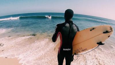 Surfer wearing Bantu Wax wetsuit looks out to sea