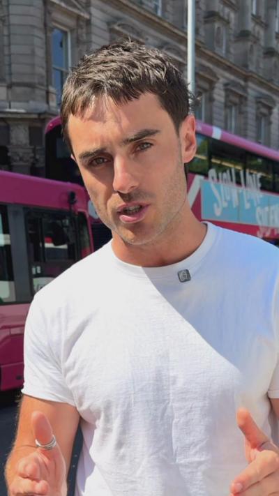 A man in a white shirt standing in front of a pink bus