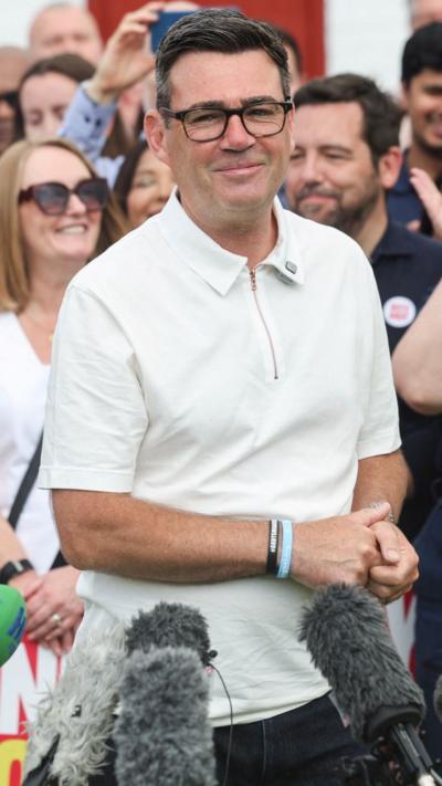 Andy Burnham stood next to a microphone