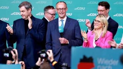 CDU leader Friedrich Merz stands on stage at the party HQ in Berlin