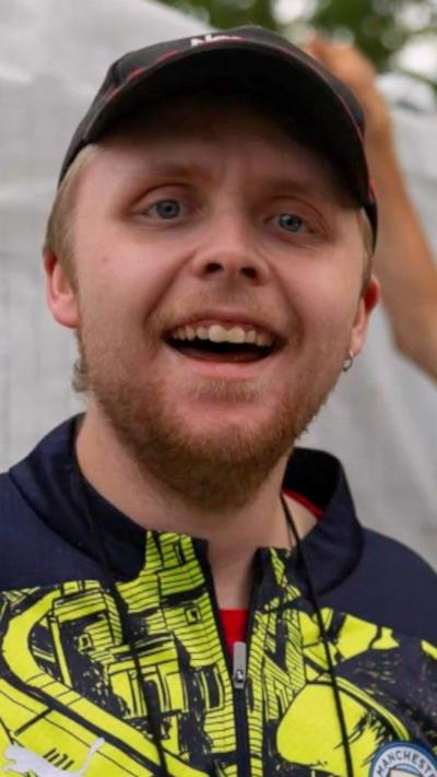 Andre Yarham, wearing a baseball cap, smiles at the camera