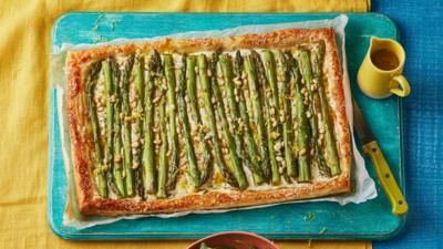 A puff pastry asparagus tart on a blue chopping board