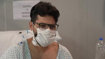 Young man in glasses, face-mask and hospital gown