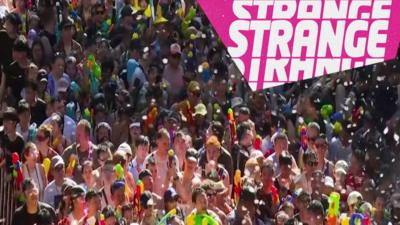 A crowd in a water fight and the Strange logo