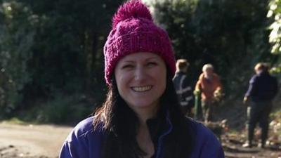 Portrait of a woman in a pink bobble hat during a gardening session