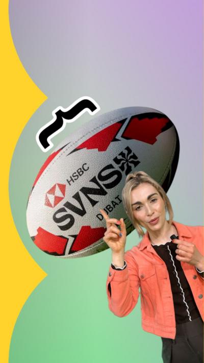 Blonde woman wearing an orange jacket over a black top points up to an image of a rugby ball behind her