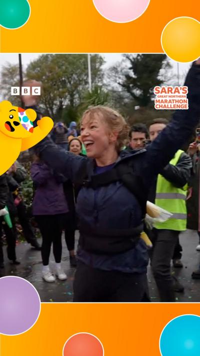 Sara raises her hands in celebration after crossing the finish line