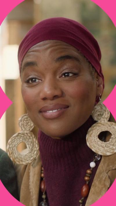 Character Funmi looks surprised. She wears a maroon headscarf and circular earrings 