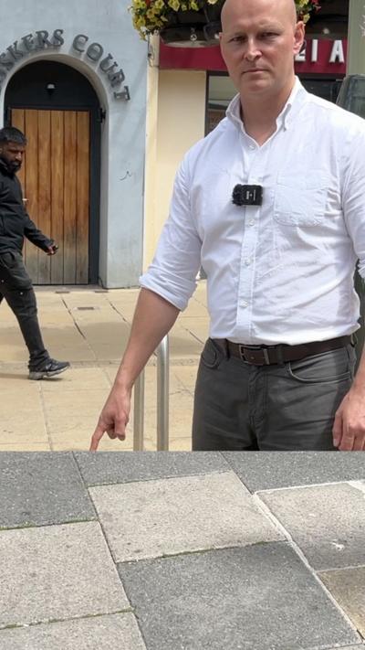Man pointing to the tarmac looking stern.