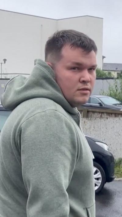 A man with a green hoody looking at the camera