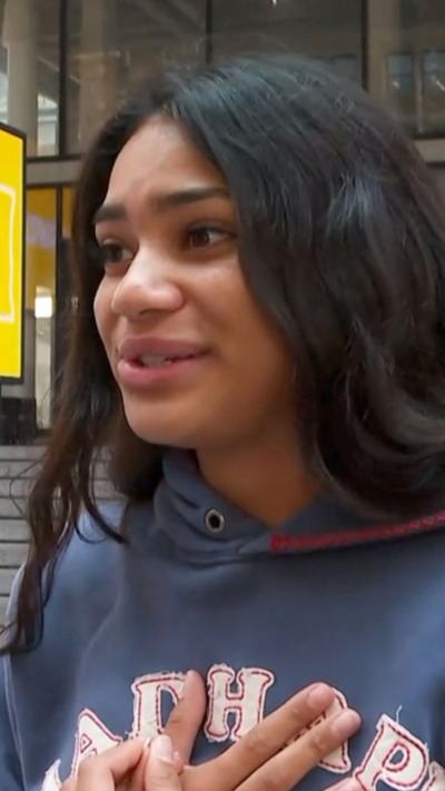 A young girl holds her hands to her heart and she speaks to the interviewer
