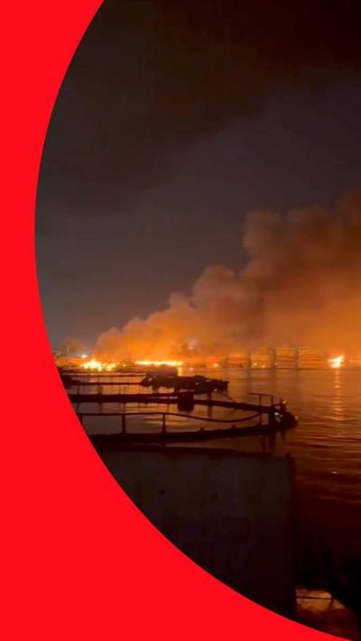 an image of a harbour on fire at night in the port city in Iran. the photo is surrounded by BBC Verify blue and green branding