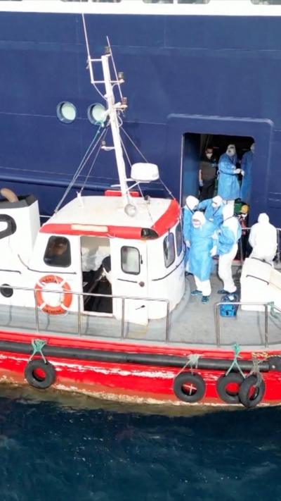 People in hazmat suit stepping into red boat