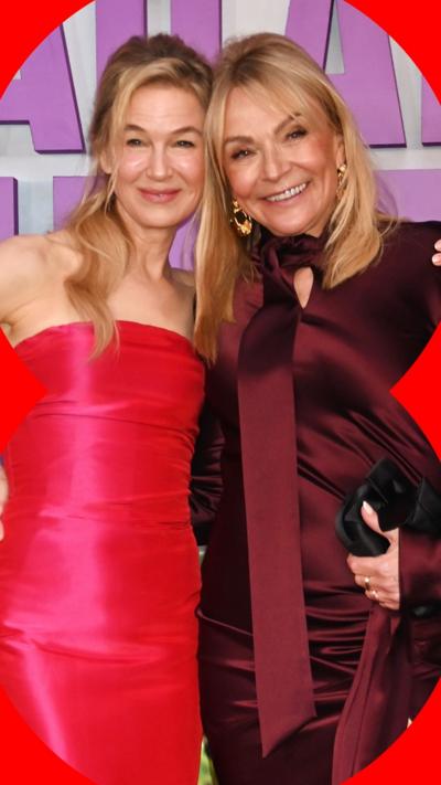 Renée Zellweger and Helen Fielding with their arms around each other, smiling. Renée wears a pink sleeveless dress, Helen wears a maroon dress with ribbon