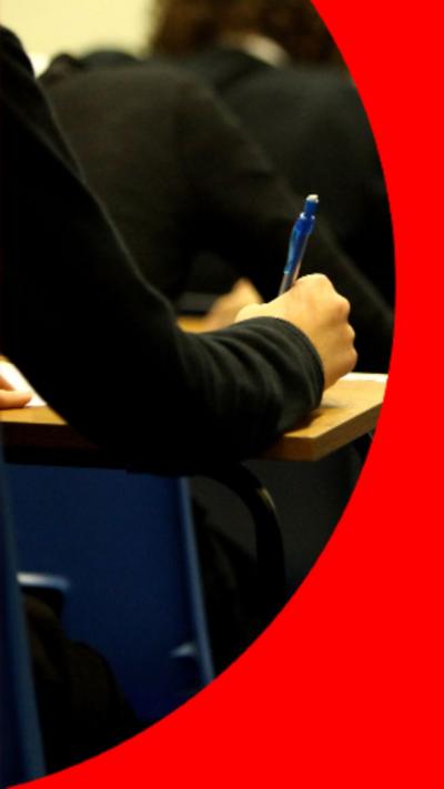 Pupils in black school jumpers taking exams in an exam hall.