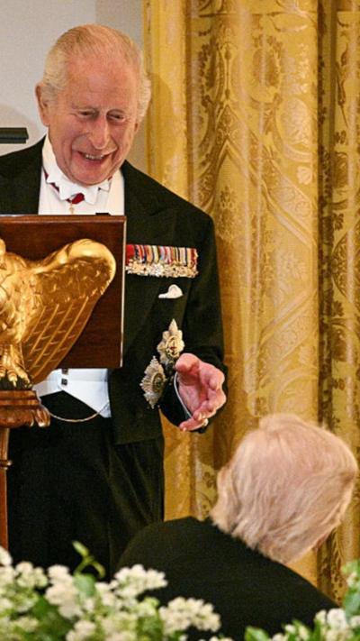 King Charles III looks down towards President Donald Trump, who is seated in front of him and facing the King, as the King addresses a dinner at the White House.
