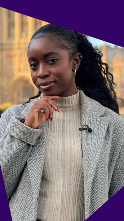 BBC News Social's Jonelle Awomoyi, looking inquisitive outside the Houses of Parliament, wearing a beige roll neck jumper and long, grey coat