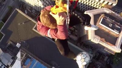 Football freestyler Tobias Becs does keepy-ups while hanging from a crane.