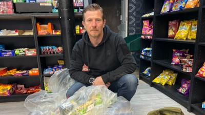 Trading Standards officer Paul Leighton in a shop with a plastic bag of vapes
