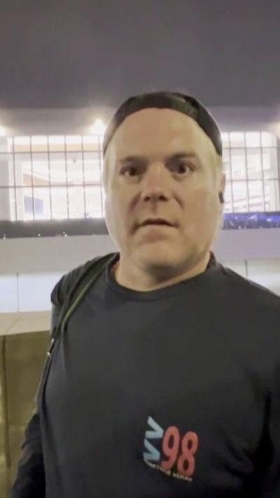 A man looks into the camera wearing a backwards hat.