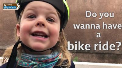 Rhoda smiles at the camera with text saying 'Do you wanna have a bike ride?'