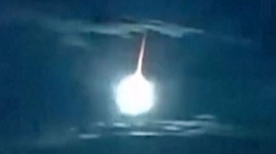 A white fireball with an orange tail illuminates an otherwise dark blue sky above Japan.
