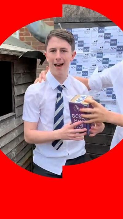 Boy in school uniform smiles. He's holding a pretend man of the match trophy.