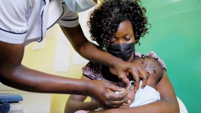 A mother cradles a baby as he receives a jab in the arm