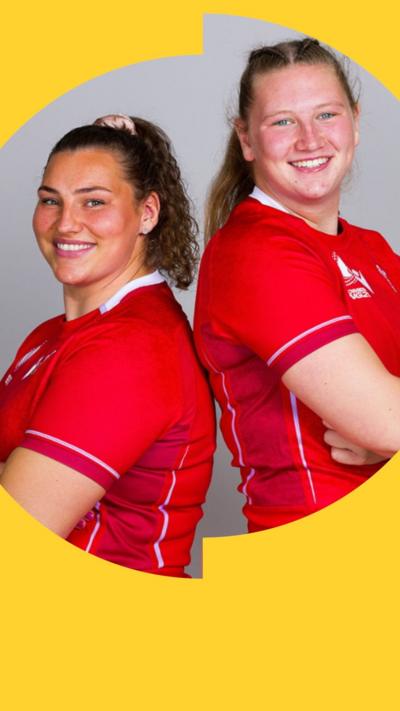 Standing back-to-back with their arms crossed, sisters Gwenllian Prys and Alaw Pyrs, who is slightly taller, both in red Wales rugby kits, smile into the camera against a plain white background